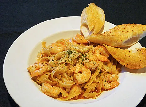 A white plate topped with pasta and shrimp.