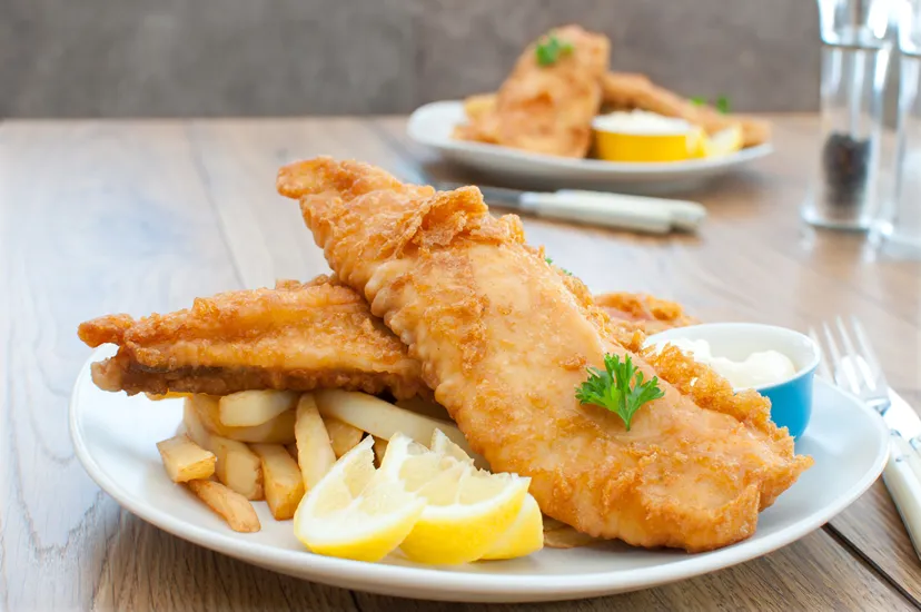 A plate of fish and french fries on a table.