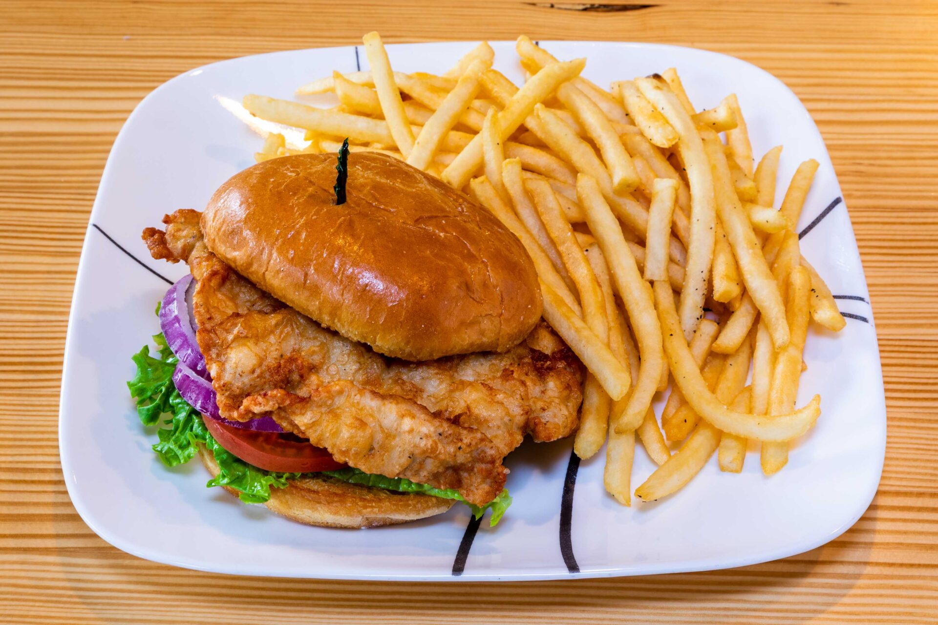 A plate of food with fries and chicken sandwich.