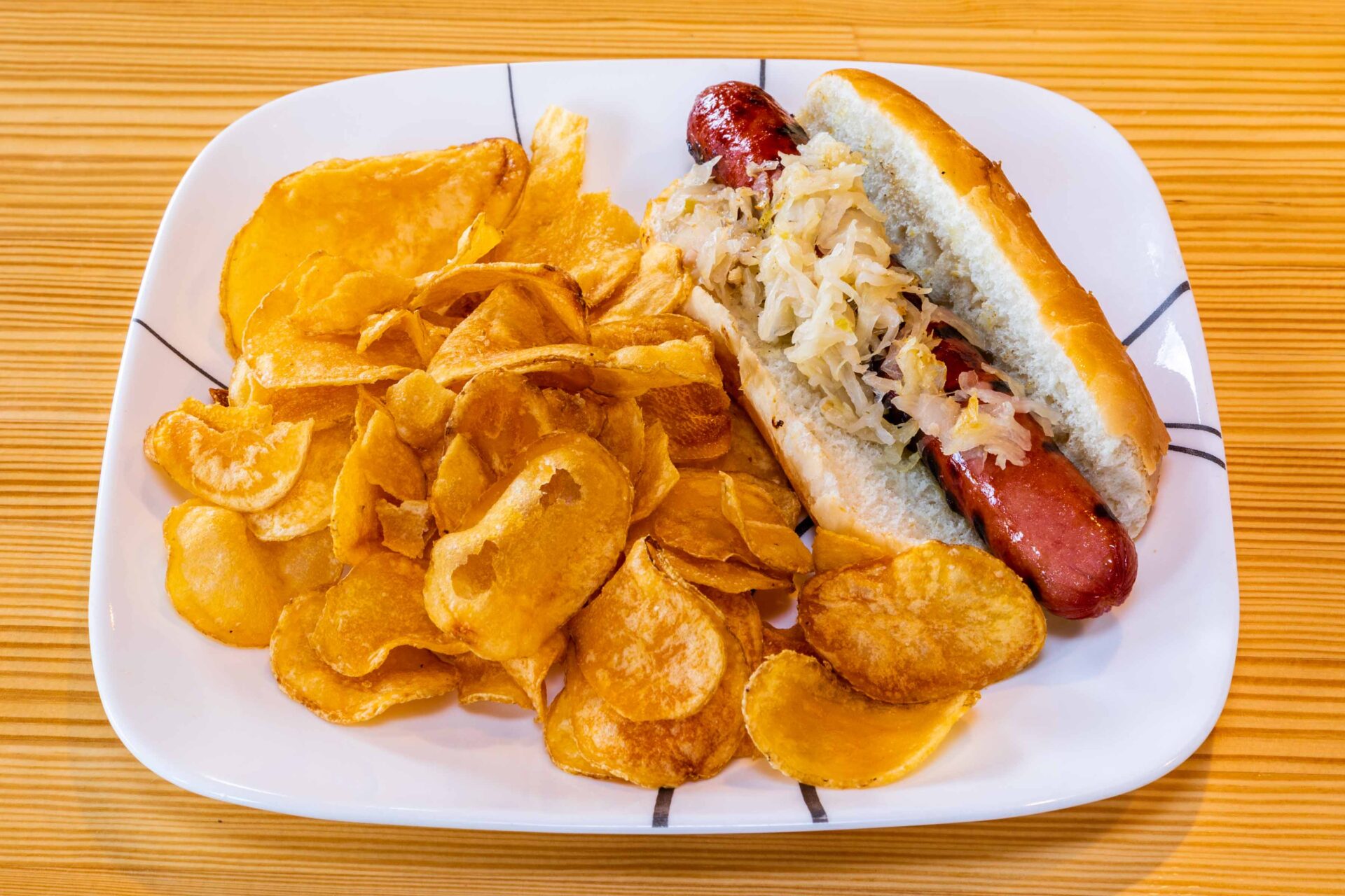 A plate of food with potato chips and hot dog.